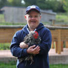 A disabled man holding a chicken and smiling