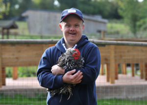 A disabled man holding a chicken and smiling